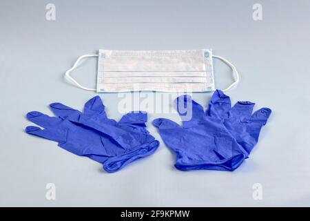 Paar dünne blaue medizinische Latexhandschuhe und Gesichtsschutz auf hellblauem Hintergrund. Medizinische Einweghandschuhe und -Maske aus Gummi. Schutzsubjekten. Stockfoto