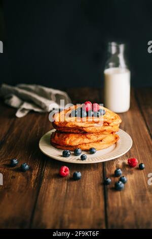 Ein antiker beiger Teller mit Pfanne, gebraten mit Heidelbeeren und Himbeeren auf einem dunklen Holztisch. Spanische Torrijas Stockfoto