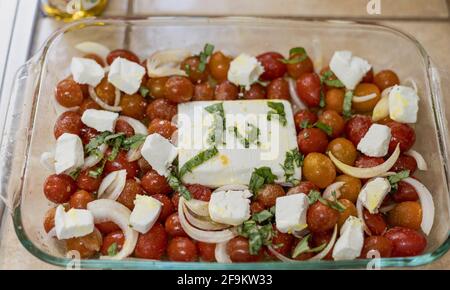 Tik Tok Feta Pasta mit Stücken Feta. Sobald die Sauce hergestellt ist, fügen Sie einfach Nudeln, Babyspinat, roten Pfeffer und Basilikum hinzu. Stockfoto