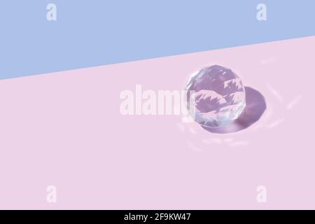 Leuchtende helle Kristallglas transparente Kugel auf pastellrosa Hintergrund. Minimal Kugel rollt kreatives Konzept Stockfoto