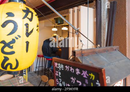 Tokio, Japan - 10. Dezember 2015: Menschen, die in Yuraku Concourse Restaurants unter den Bahngleisen speisen, sind auf Yakitori spezialisiert Stockfoto