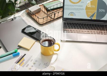 Nahaufnahme des Tisches mit Laptop und einer Tasse Kaffee bei Modernes Büro Stockfoto