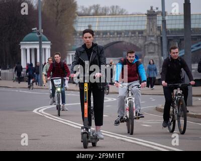 Moskau, Russland. April 2021. Eine junge Frau, die auf einem Elektroroller in ihrem Hintergrund gesehen wird, ist auf dem Pushkinskaya-Ufer im Gorki-Park auf Fahrrädern unterwegs. (Foto: Alexander Sayganov/SOPA Images/Sipa USA) Quelle: SIPA USA/Alamy Live News Stockfoto