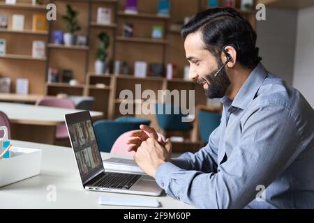 Lächelnder indischer Geschäftsmann, der Videoanruf mit verschiedenen Menschen auf einem Laptop hat. Stockfoto