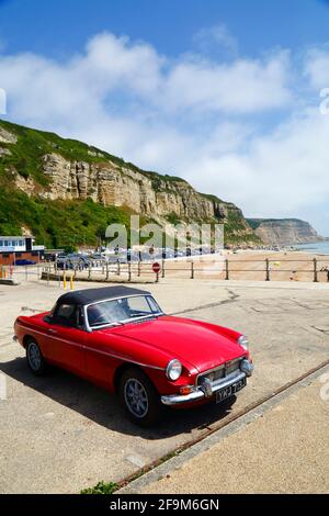 Red MG MGB Oldtimer auf dem Parkplatz Rock-A-Nore, East Cliffs im Hintergrund, Hastings, East Sussex, England, Großbritannien Stockfoto