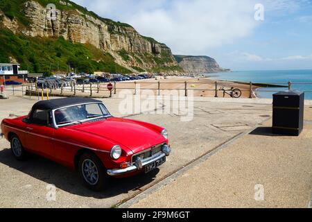 Red MG MGB Oldtimer auf dem Parkplatz Rock-A-Nore, East Cliffs im Hintergrund, Hastings, East Sussex, England, Großbritannien Stockfoto