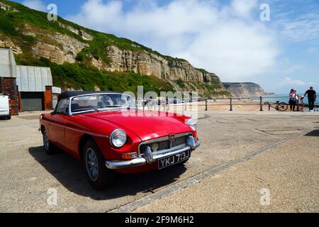 Red MG MGB Oldtimer auf dem Parkplatz Rock-A-Nore, East Cliffs im Hintergrund, Hastings, East Sussex, England, Großbritannien Stockfoto