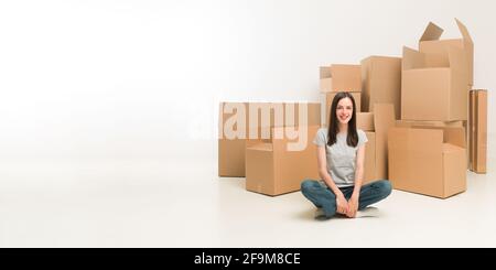 glückliche junge Frau am Boden umgeben von Umzugskartons Stockfoto