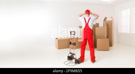 Rückansicht der Lieferung Mann mit Blick auf Haufen von Kartons, hält seine Hände auf seinen Kopf besorgt auf der Suche Stockfoto