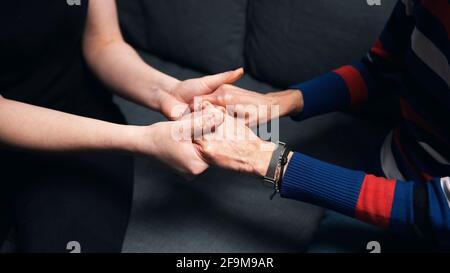 Junge Person, die die Hände einer älteren Frau hält. Hochwertige Fotos Stockfoto