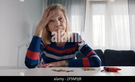 Besorgte alte Frau geht das Geld aus. Münzen auf dem Tisch zählen. Hochwertige Fotos Stockfoto