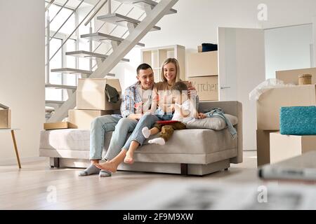 Ein glückliches Familienpaar mit einem kleinen Sohn, der sich am Tag des Umziehendes in einem neuen Zuhause auf der Couch entspannt. Stockfoto