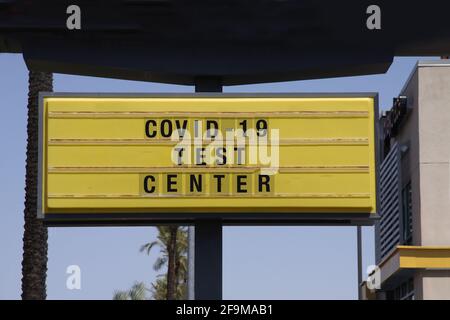 Plakatwand mit der Aussage Covid-19 Test Center. Mit Palmen und blauem Himmel Hintergrund. Konzept des Coronavirus-Pandemieimpfstoffs. Stockfoto