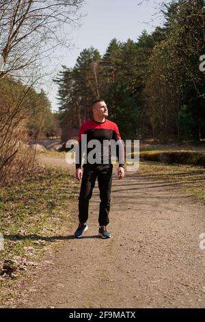 Ein Mann in Sportkleidung auf einem Waldweg. Ein Mann nach einem morgendlichen Joggen spaziert im Wald Stockfoto