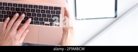 Frau hält Laptop auf ihrem Schoß und tippt darauf Nahaufnahme Stockfoto