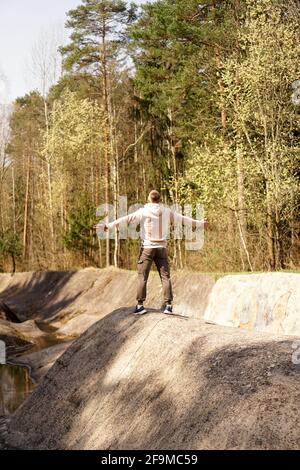 Ein junger Mann steht auf einem kleinen Berg im Bereich eines Gebirgsflusses Stockfoto
