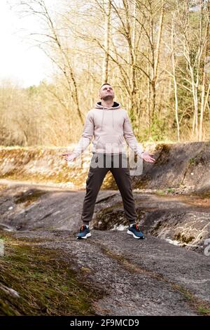 Ein junger Mann steht auf einem kleinen Berg im Bereich eines Gebirgsflusses Stockfoto