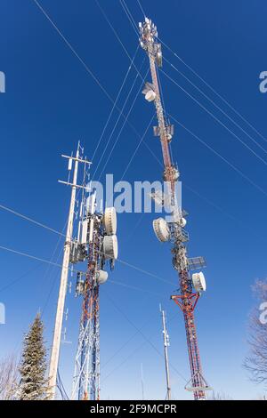 Professionelle Fotografie von zwei 3G- und 4G-Telekommunikationstürmen mit angeschlossenen Antennen, Netzwerk-Repeatern und verschiedenen miteinander verbundenen Drähten. Stockfoto