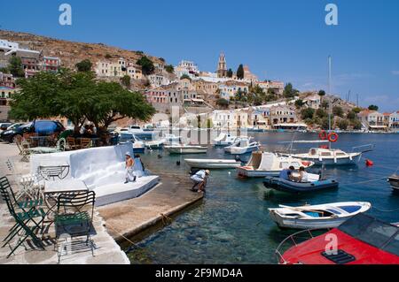 Symi - Griechenland - August 17 2009 : Charmanter kleiner Hafen mit bunten Vergnügungsbooten, die an einer wunderschönen malerischen Bucht liegen, die von einem neoklassizistischen Gebäude umgeben ist Stockfoto