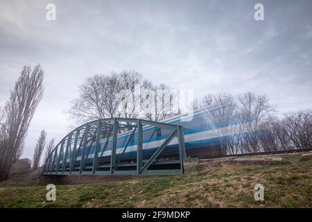 Alte rostige Fachwerkbrücke mit fahrender Güterbahn über den Fluss Orljava. Fahrender Zug. Stockfoto