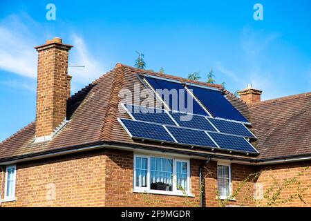 Ziegelhaus mit Solarzellen und Solarwasserheizpaneelen auf dem Dach in Hertfordshire, Großbritannien Stockfoto