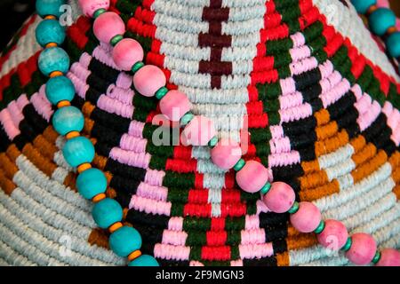 American Indian Dekor Hintergrund - rosa und türkis Perlen drapiert Auf einem bunten Textil gewebten Design Nahaufnahme und flachen Fokus Stockfoto