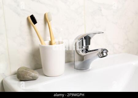 Im Badezimmer stehen zwei Bambuszahnbürsten in einem Glas. Umweltfreundliches Konzept. Horizontale Ausrichtung. Stockfoto
