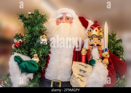 Künstliches Dekor Weihnachtsmann Figur hält einen Baum und ein nussknacker und eine Liste von guten Jungen und Mädchen gegen Verschwommener Hintergrund - Taille nach oben Stockfoto