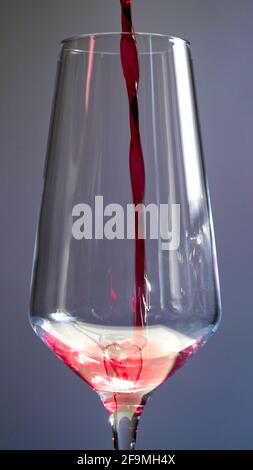 Bei Nahaufnahme eines Sommeliers gießt ein Kellner Rotwein, Saft oder Champagner in ein Glas. Alkohol in einem Glas Stockfoto