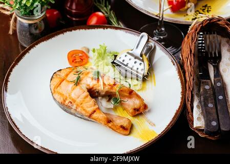 Gegrillter Fisch auf einem Teller mit Gemüse und Sauce Stockfoto