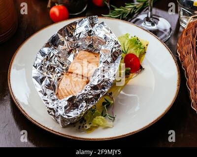Gegrillter Fisch auf einem Teller mit Gemüse und Sauce Stockfoto
