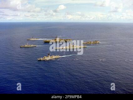 Eine Hafenansicht von Schiffen des Flugzeugträgers USS MIDWAY (CV-41), die in Formation unterwegs sind. Zu den Schiffen gehören von links die Fregatte USS MEYERKOD (FF-1058) und die Fregatte USS JOHN A. MOORE (FFG-19), vordere Reihe; das Schlachtschiff USS NEW JERSEY (BB-62), der Flugzeugträger USS MIDWAY (CV-41) und die Fregatte USS FRANCIS HAMMOND (FF-1067), Mitte und der Flottenöler UST-MISPILAO-105 hinten Stockfoto