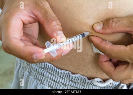 Diabetes-Patient bekommt eine Insulininspritze in Bauchbereich über weißem Hintergrund. Stockfoto