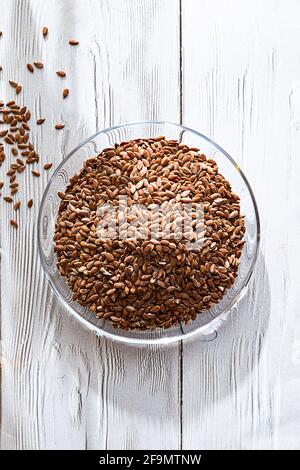 Leinsamen in Glasschale auf dem weißen Holztisch. Nahaufnahme und Kopierbereich. Stockfoto