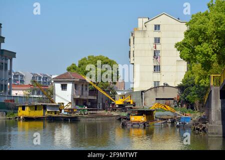 Bauarbeiten am Rande des Großen Kanals von Jiaxing, gelbe Krane für Land- und Wassernutzung. Stockfoto