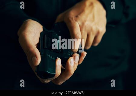 Herrenhände prüfen im Revolverfass auf Kugeln. Nahaufnahme der Waffe nachladen. Guy bereitet Pistole für Schüsse vor. Schusswaffe zur Verteidigung oder zum Angriff. Stockfoto