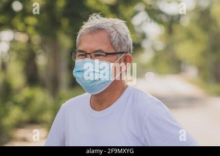 Alter Mann tragen chirurgische Maske schützen Coronavirus covid19 im Freien City Park Lifestyle neue normale, pensionierte Mann trainieren in der Morgen Stockfoto