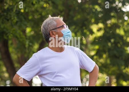 Alter Mann tragen chirurgische Maske schützen Coronavirus covid19 im Freien City Park Lifestyle neue normale, pensionierte Mann trainieren in der Morgen Stockfoto