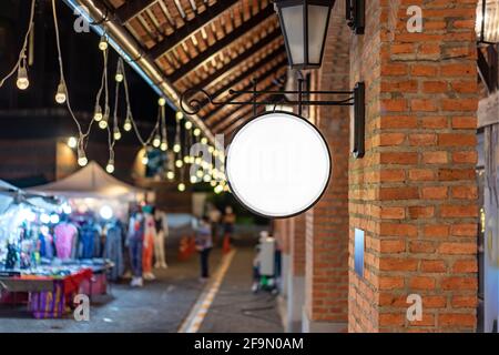 Der Circle White Lightbox hat an der Wand vor dem Backsteinpfosten in einem Tungsten Ambient Umgebung Vintage Shopping Community Mall gehängt. Stockfoto