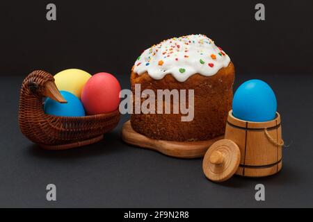 Osterkuchen und bunte Ostereier im Weidenkorb. Stockfoto