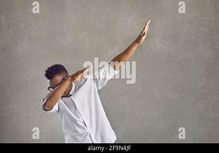 Junger schwarzer Mann, der einen beliebten Tanztanz macht, isoliert auf Grauer Betonhintergrund Stockfoto