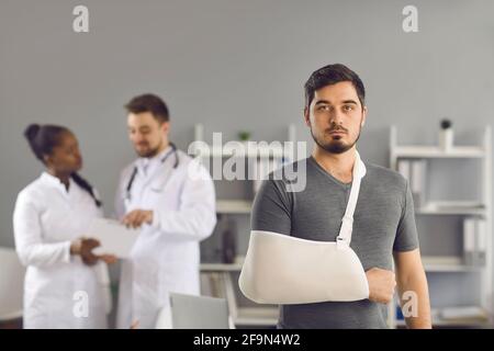 Ernsthafter Mann Patient mit gebrochenem Arm, eingewickelt auf orthopädischen Verband Hochformat Stockfoto