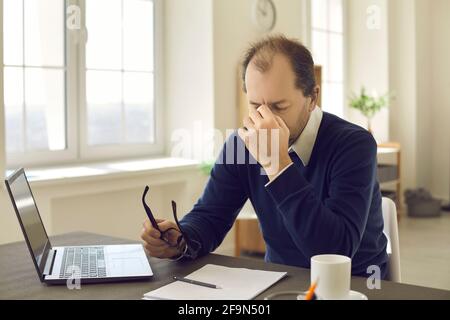 Reifer Mann hält Brille massiert Nase fühlen Augenbelastung nach Arbeiten Sie auf einem Laptop Stockfoto