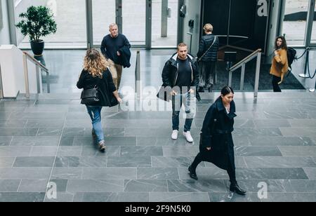 Blick auf Geschäftsleute in der Lobby. Geschäftsleute, die durch einen Büroflur laufen. Stockfoto