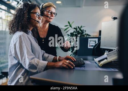 Zwei weibliche Kollegen arbeiten zusammen, während sie am Computer arbeiten und im Büro arbeiten. Geschäftsfrauen arbeiten gemeinsam an einem Projekt im Büro. Stockfoto