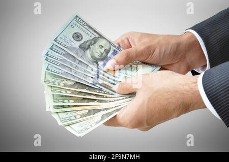 Geld - Hände mit Banknoten (US-Dollar oder USD) Auf grauem Hintergrund Stockfoto