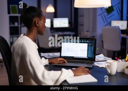 Afrikanischer Ingenieur schriftlich Baumeister Strategie auf Papierkram während Analyse architektonischen Bauplan auf Laptop-Computer. Professioneller Architekt, der bei kreativer Ingenieurarchitektur arbeitet Stockfoto