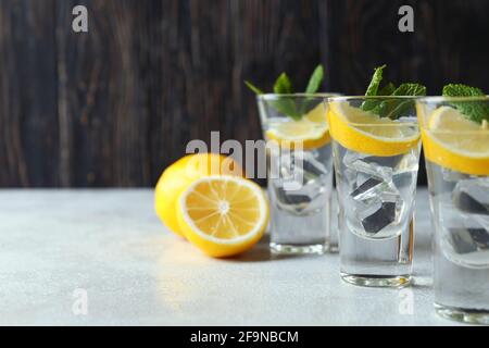 Schüsse mit Zitronenscheibe und Minze auf einem weißen Tisch mit Struktur Stockfoto