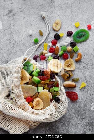 Verschiedene getrocknete Früchte und Nüsse in einem Öko-Beutel auf Ein grauer Betonhintergrund Stockfoto