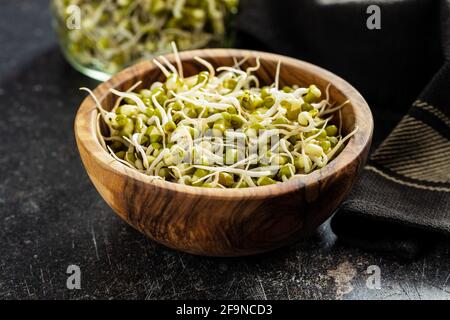 Gekeimt grüne Mungbohnen. Mungsprossen in der Schüssel auf dem schwarzen Tisch. Stockfoto